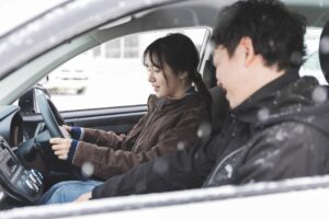 車内でハンドルを握り運転する女性と助手席に座る男性