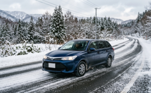 雪の積もり始めた路面を走行する普通自動車